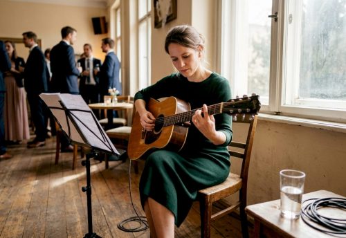 Was ist eine musikalische Begleitung: Tipps für Hochzeiten 4 Bei der Hochzeit sorgt eine Musikerin mit ihrer Gitarre für die passende musikalische Begleitung.