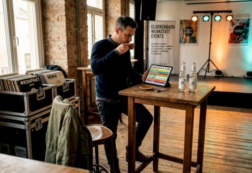 10 Tipps für Messepartys in München: Kreative Ideen und DJ-Erfolg 6 In einem Raum mit Backstein und Holz bereitet ein DJ-Setup mit Laptop, Kabeln und Eventtechnik die Unterhaltung für eine Messeparty in München vor.