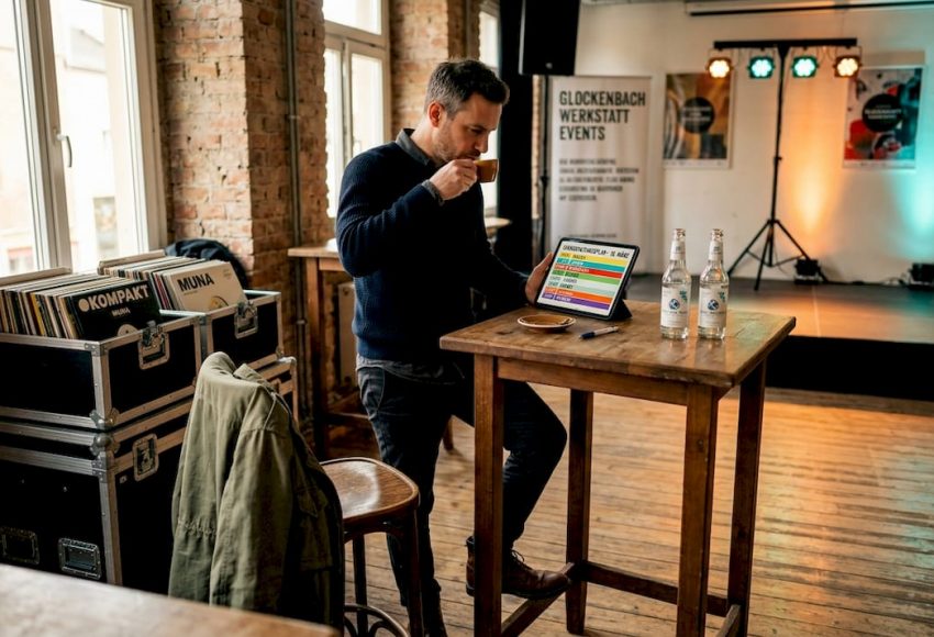In einem Raum mit Backstein und Holz bereitet ein DJ-Setup mit Laptop, Kabeln und Eventtechnik die Unterhaltung für eine Messeparty in München vor.