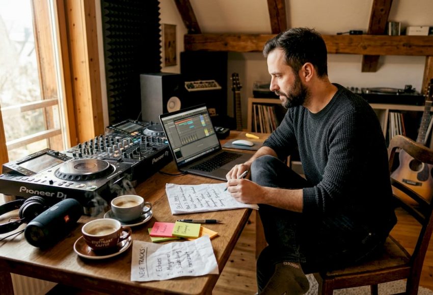 Vorteile maßgeschneiderter Musikkonzepte für Events 5 In einem Studio sitzt ein DJ am Laptop und steuert den Pioneer DJ Controller, um die Musikkonzepte für Events passend zu planen.