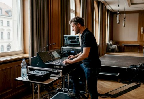 Vorteile hochwertiger Veranstaltungstechnik in München 4 Ein Techniker bedient in München ein Yamaha Mischpult bei der professionellen Abstimmung von Ton und Veranstaltungstechnik im Eventsaal.