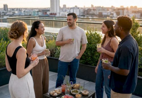Was ist ein After-Work-Event? Dein Guide 2026 5 Bei einem entspannten After-Work-Event auf der Dachterrasse sprechen Kollegen bei Drinks in der Abendsonne miteinander und nutzen die lockere Atmosphäre.
