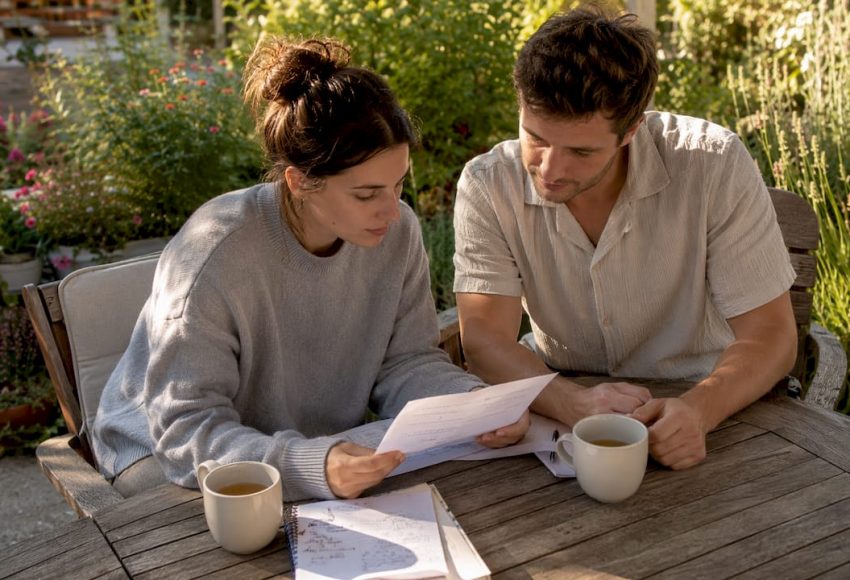 Song-Auswahl für Events: Ihr Leitfaden für Hochzeit & DJ 8 Ein Paar sitzt am Gartentisch und bespricht mit Papieren die Song-Auswahl für die Hochzeit im Freien.